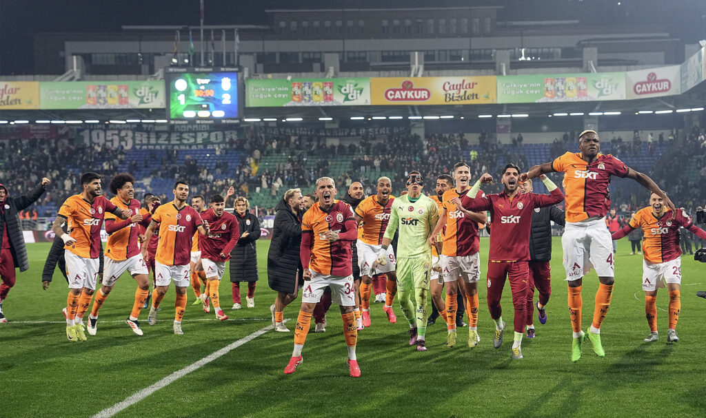 Galatasaray 2025 Süper Lig Champions walk onto the pitch for a UEFA Champions League match, with the competition logo and a packed stadium in the background.