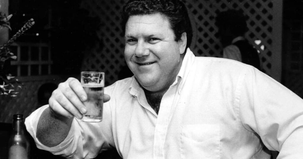 Fans toast to George Wendt Cheers in a bar, with a Cheers episode featuring Norm on TV.